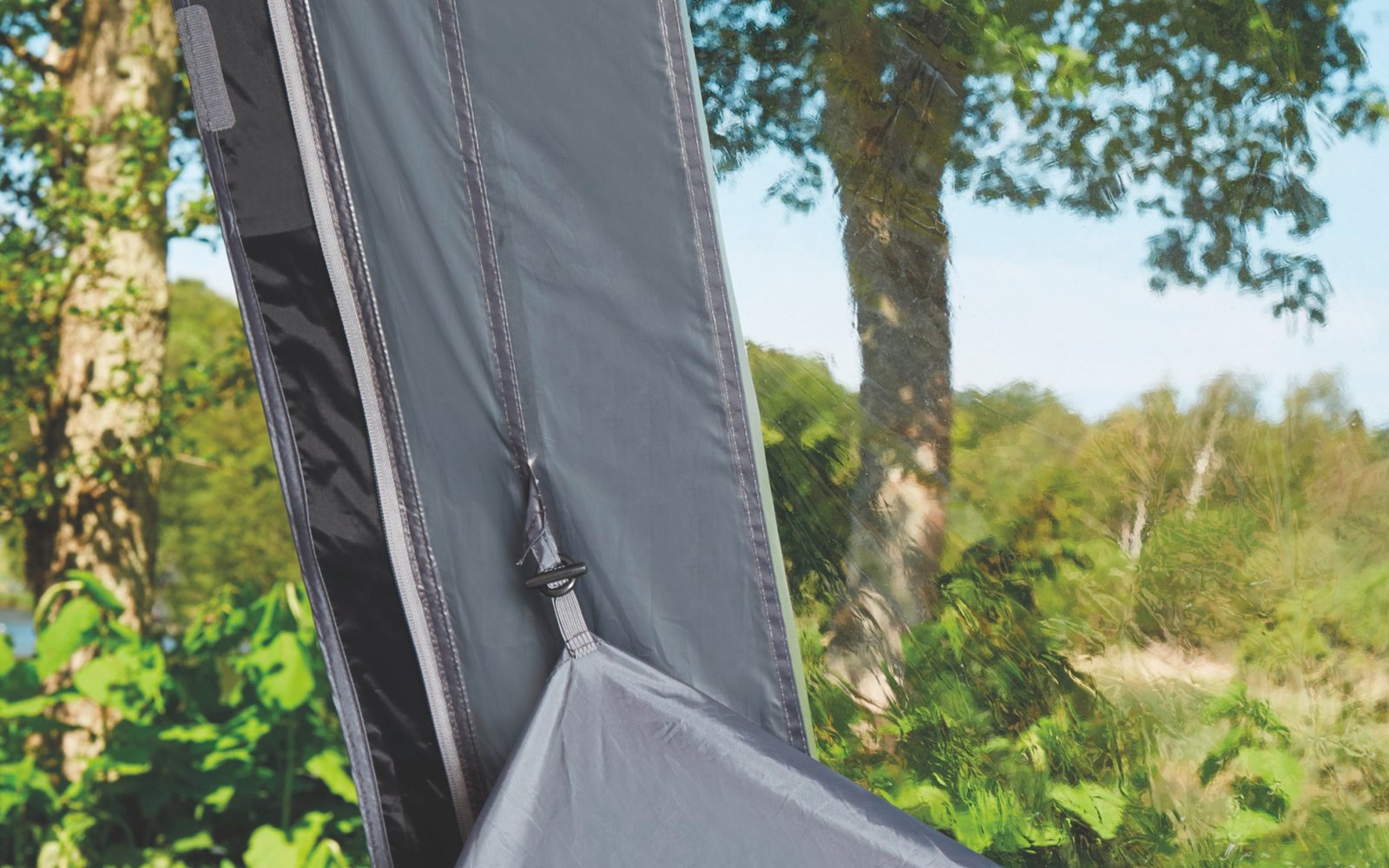 Zuschnitt eines Stuhls mit grauem Stoff vor grünen Bäumen im Freien