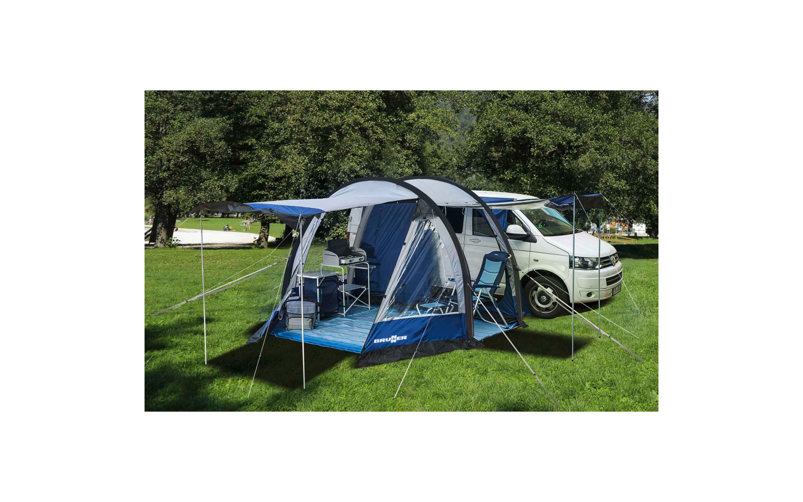Tenda da campeggio con tettoia aperta accanto a un camper bianco su prato verde