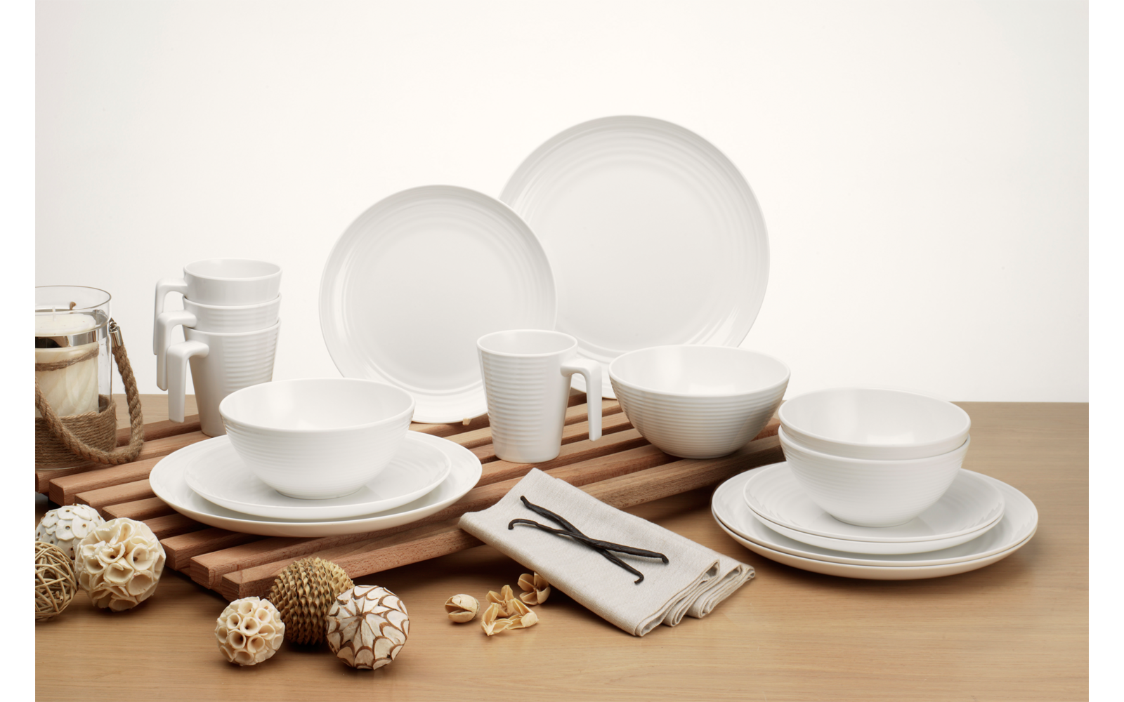 Weißes Geschirr mit Tellern, Schalen und Tassen auf einem Holztisch