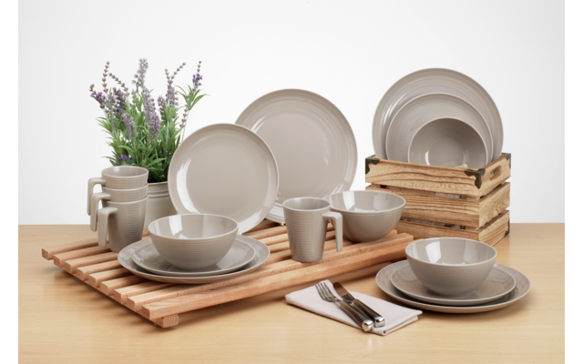 Verschiedene graue Keramikgeschirrteile auf einem Holztablett und Holztisch, neben einem Krug mit Lavendel und einer Holzkiste