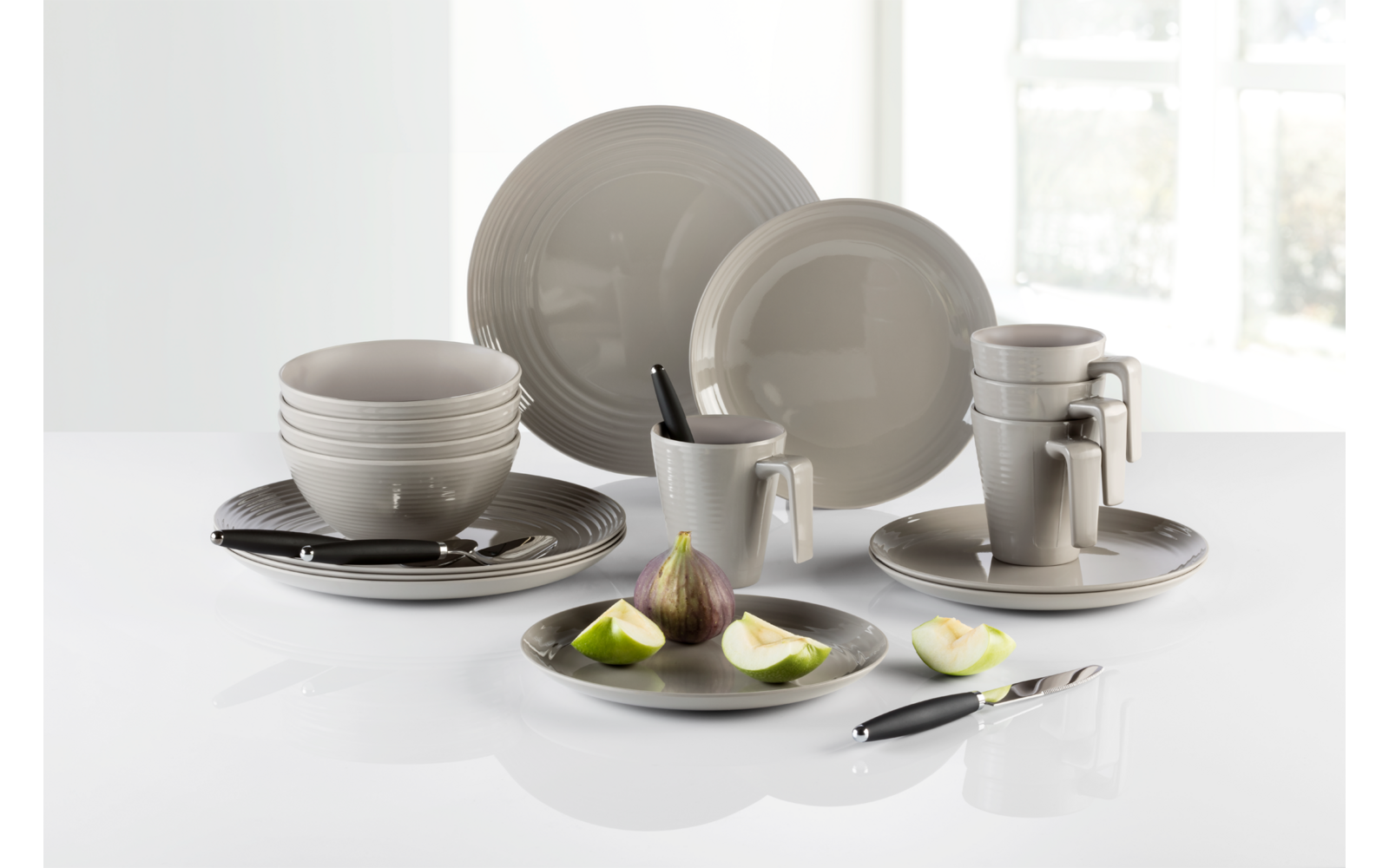 Verschiedene weiße Teller, Tassen und Gläser auf einer weißen Oberfläche mit dekorierter Vorspeise