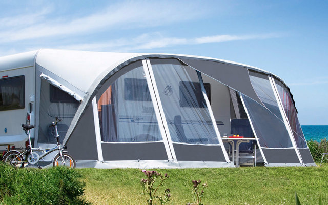 Auvent attaché à un camping-car sur une pelouse verte avec un ciel bleu en arrière-plan