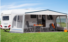 Camping-car avec auvent attaché sur une pelouse verte