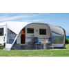Camping-car avec auvent attaché sur une pelouse verte sous un ciel bleu