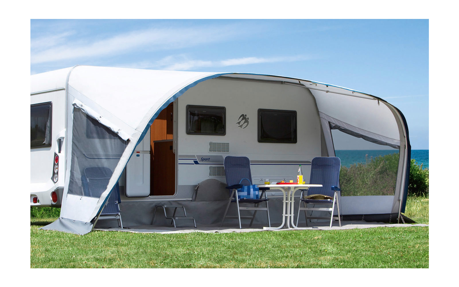 Camping-car avec auvent attaché sur une pelouse verte sous un ciel bleu