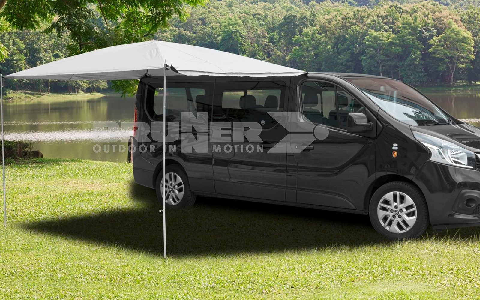 Schwarzer Campervan mit ausgefahrenem grauen Sonnenschutz auf einer grünen Wiese, im Hintergrund Bäume
