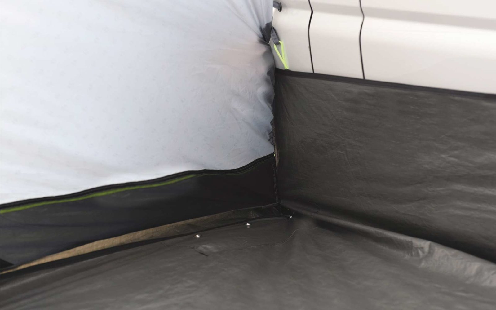 Ecke eines Zimmers mit weißer Wand und schwarzem Bodenbelag