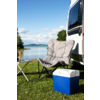 Silla plegable y nevera sobre hierba junto a una autocaravana con un lago y montañas al fondo