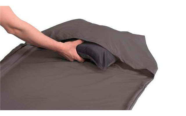 Hand legt ein zusammengefaltetes graues Tuch auf ein graues Bettlaken