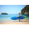Frau am Strand mit blauem Stand-Up-Paddle-Board neben dem Wasser