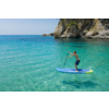 Person steht auf einem Stand-Up-Paddle-Board im klaren, türkisfarbenen Wasser neben einer Felsklippe