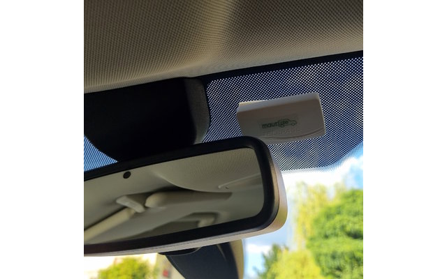Innenansicht eines Fahrzeugs mit Blick auf den Rückspiegel und den Himmel durch die Windschutzscheibe