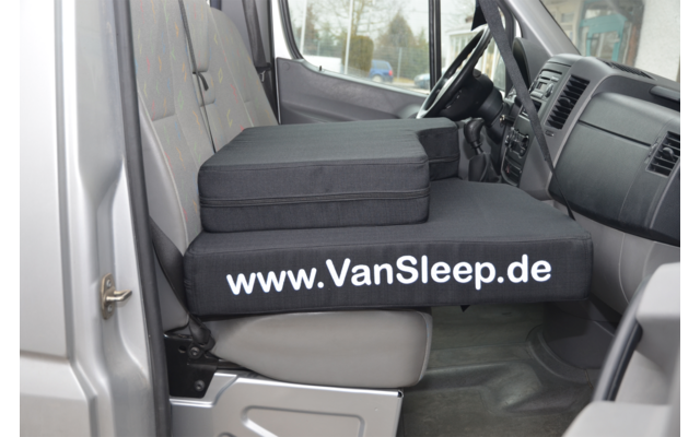 Innenraum eines Fahrzeugs mit einem Sitz umgebaut als Schlafplatz mit der Aufschrift www.VanSleep.de