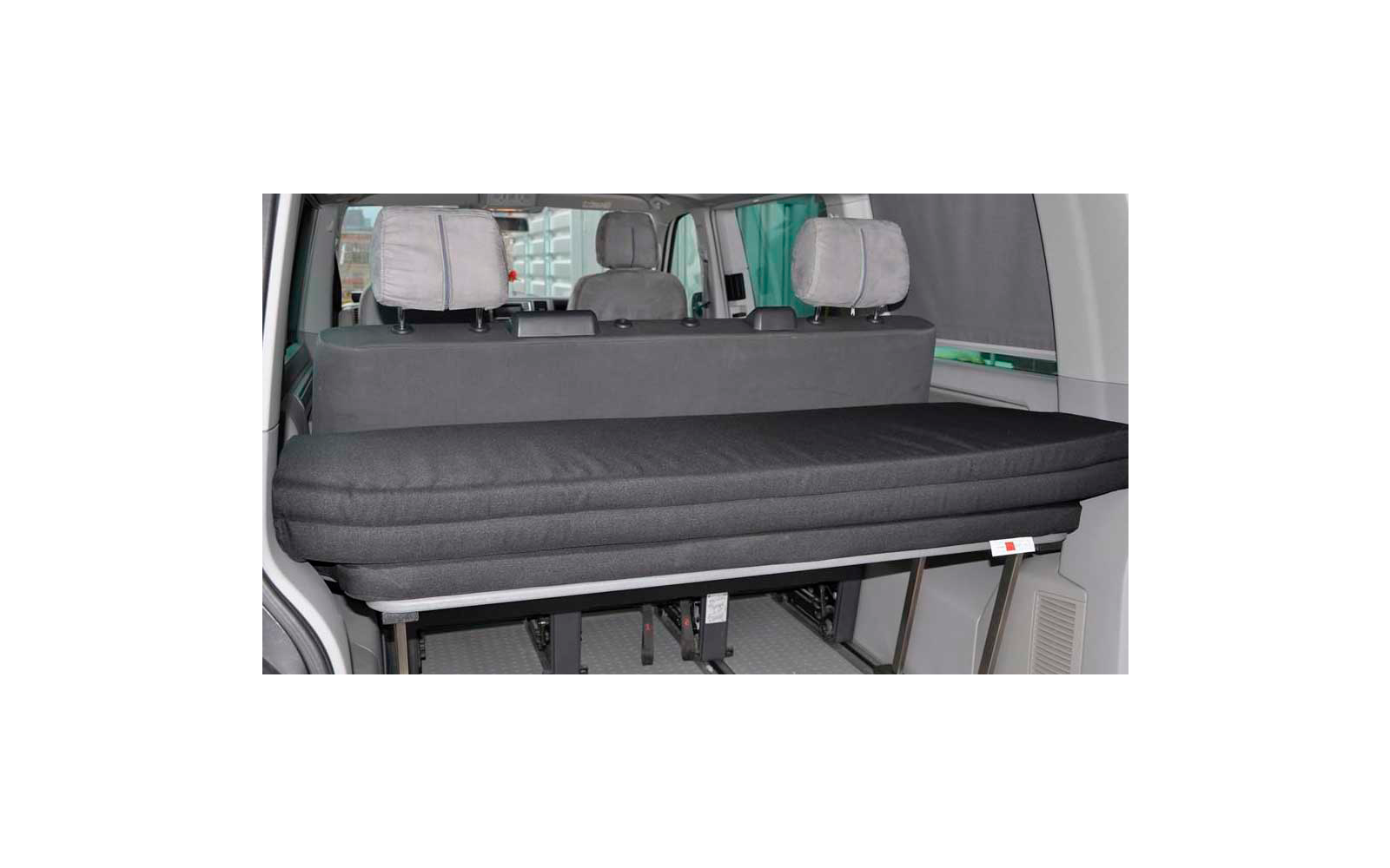 Black folding bed inside a vehicle with three headrests in the background