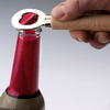 Hand öffnet mit einem Kapselheber eine Flasche mit rotem Verschluss