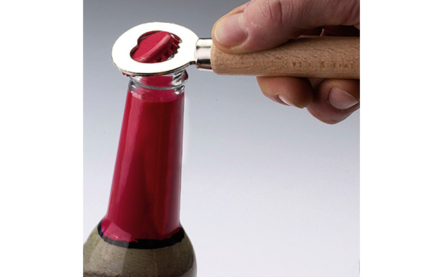 Hand öffnet mit einem Kapselheber eine Flasche mit rotem Verschluss