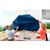 Un homme et une femme fixent une housse bleue sur un camping-car blanc