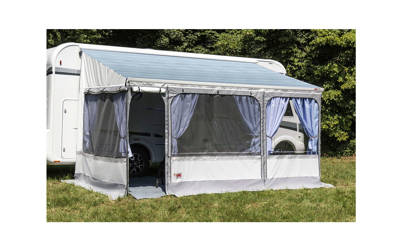 White camper van with closed gray awning on a grassy field