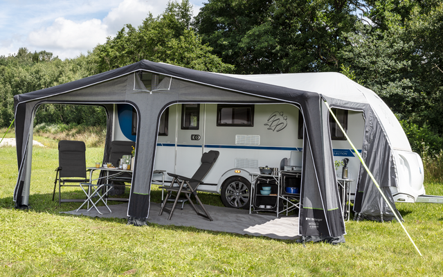 Caravan with awning on green grass under blue sky
