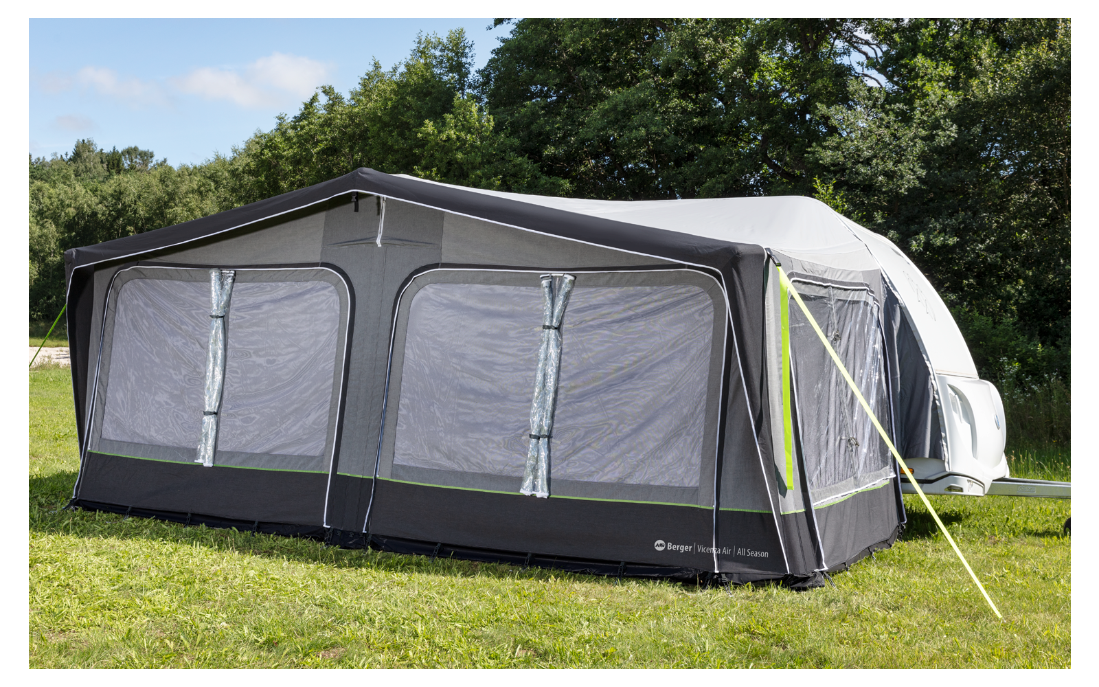 Large gray caravan awning with multiple windows, attached to a caravan on a grassy area with trees in the background