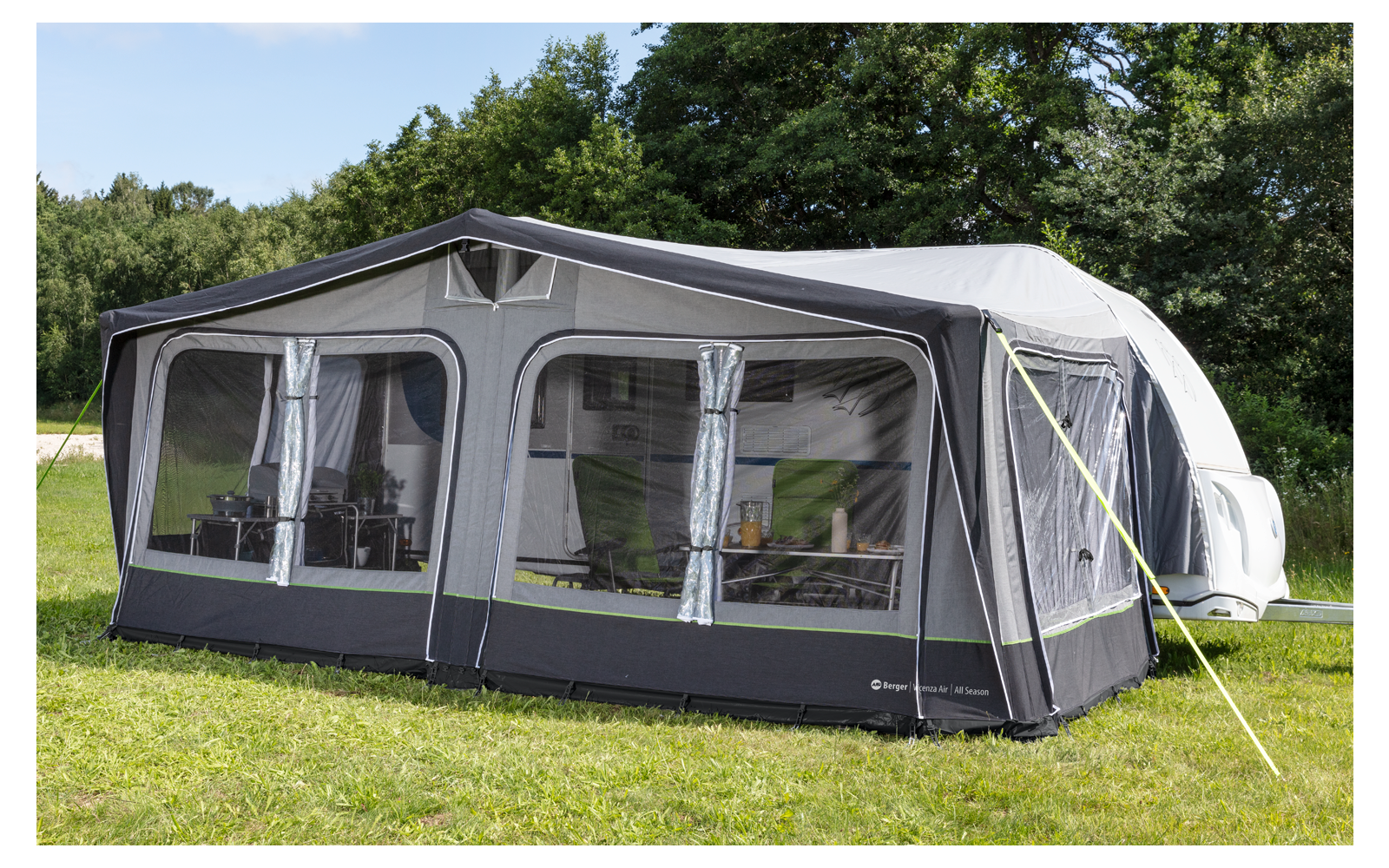 A large gray caravan awning stands on a grassy area with trees in the background