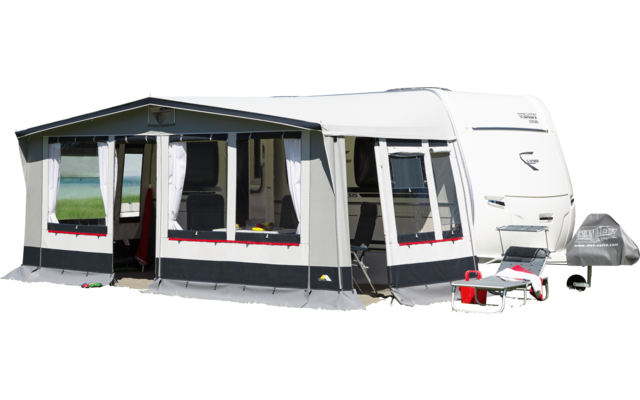 Caravan with attached awning on a green lawn under blue sky