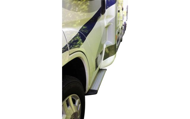 Camping-car stationné sur un chemin pavé à côté d'une haie