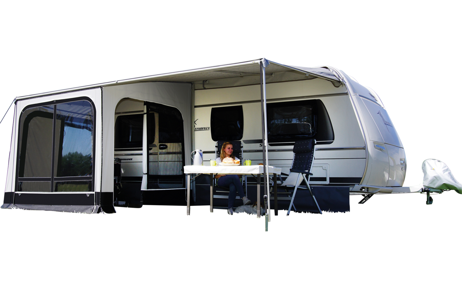 Caravane avec auvent et table sur une prairie verte sous un ciel bleu