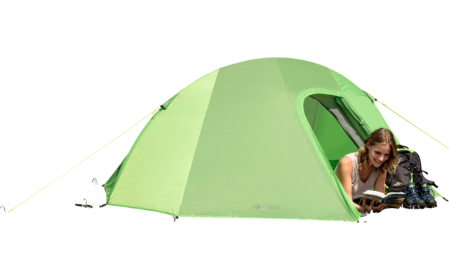 Grünes Zelt auf einer Wiese mit einer liegenden Frau, die liest, im Hintergrund Berge und blauer Himmel
