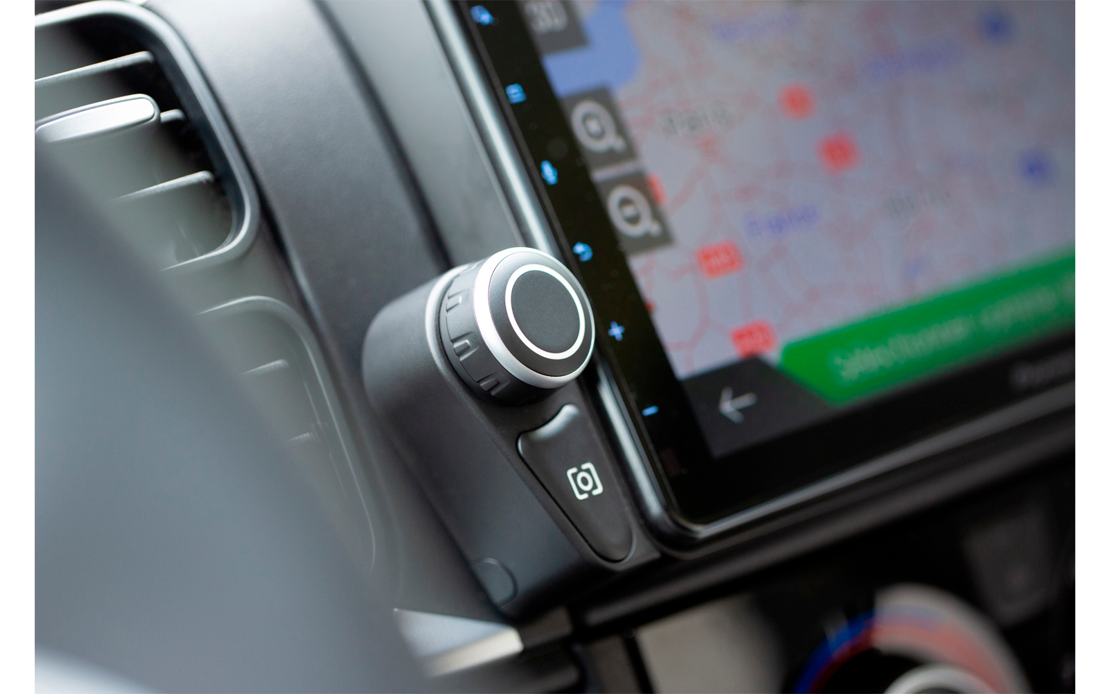 Close-up of a car radio with a rotary knob and a navigation screen