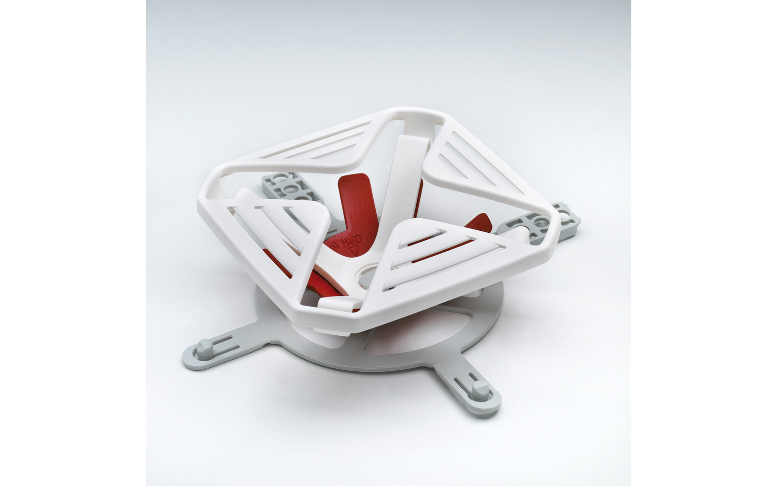 Dreieckige weiße Kunststoff-Eckablage mit roten rutschfesten Einsätzen auf weißem Hintergrund