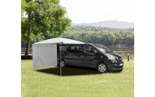 Schwarzer Transporter mit grauem Seitenschutz und Markise auf einer Wiese neben einem See