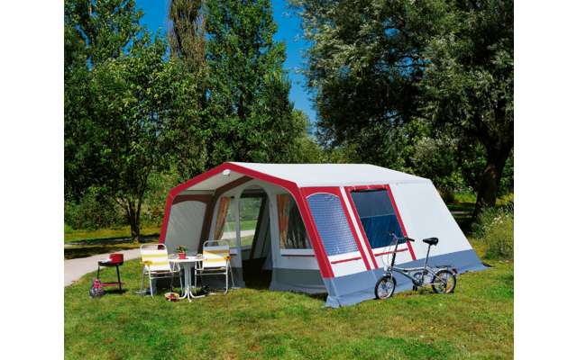 Großes Zelt mit Vorzelt auf einer grünen Wiese, zwei Fahrräder davor, sonniger Tag mit blauem Himmel