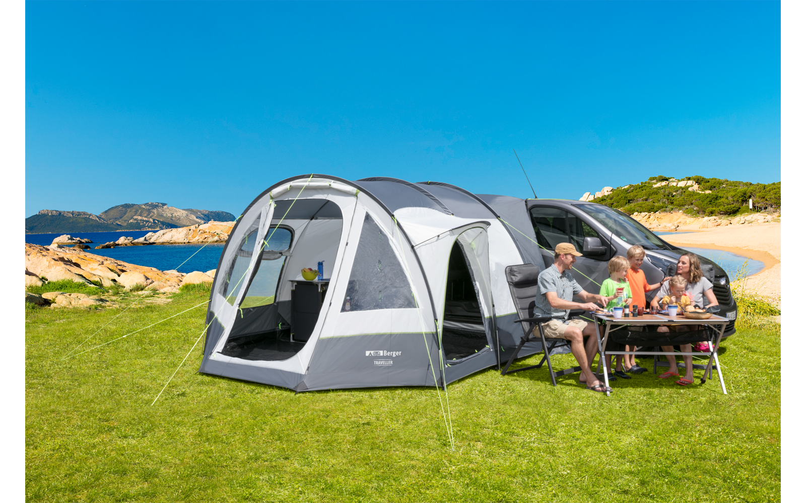 Familie sitzt an einem Campingtisch vor einem weißen Wohnmobil mit angebautem Zelt