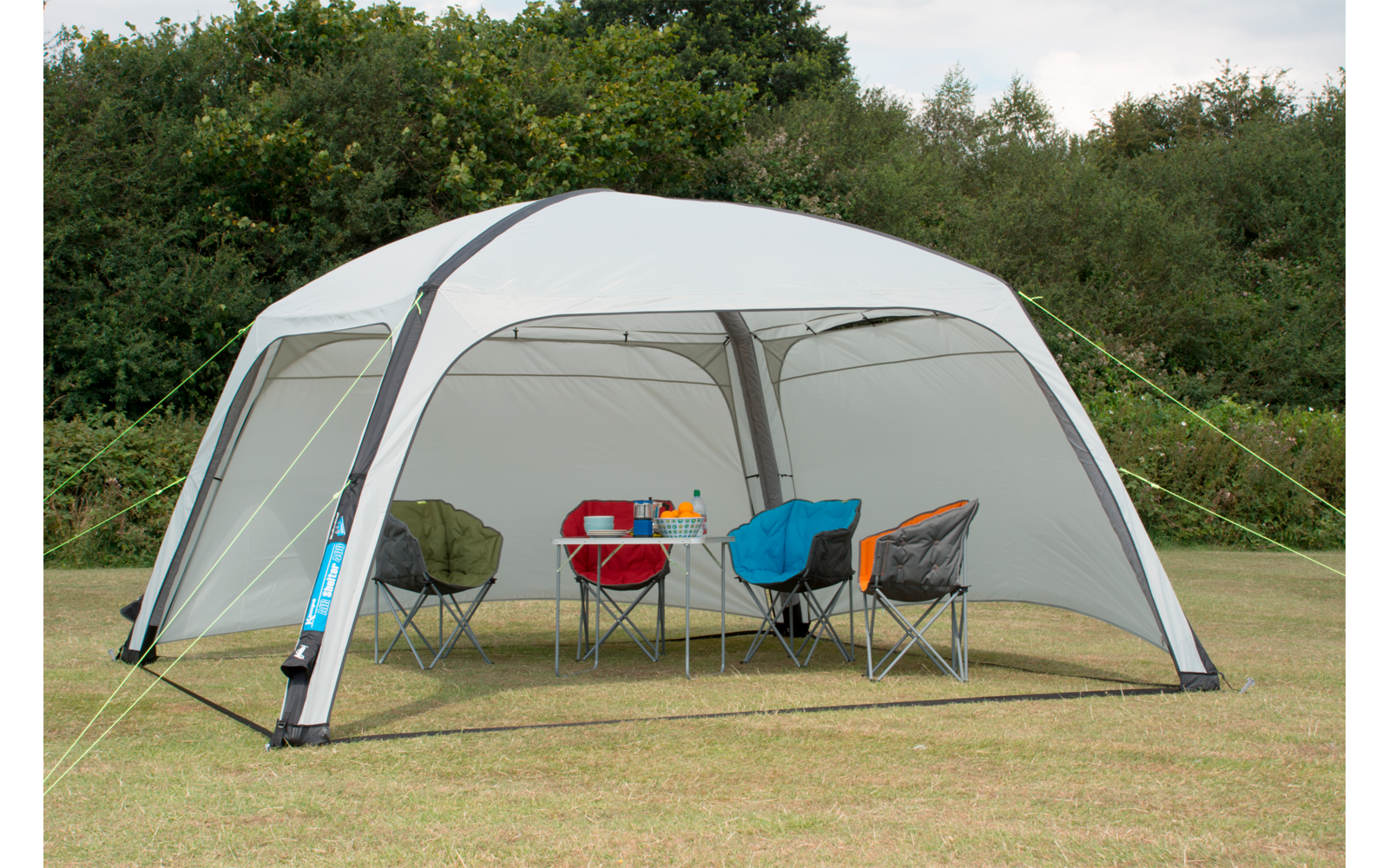Weißes Zeltdach mit vier Campingstühlen und einem Tisch auf Grasfläche