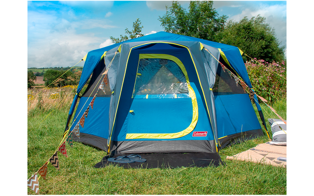 Blaues und grünes Zelt steht auf einer Wiese unter blauem Himmel