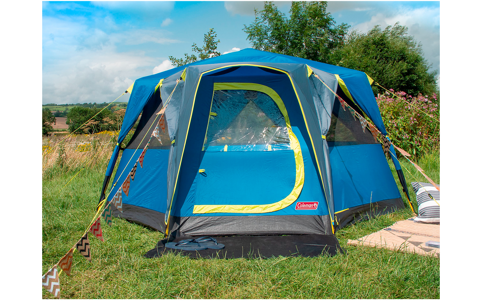 Blaues und grünes Zelt steht auf einer Wiese unter blauem Himmel