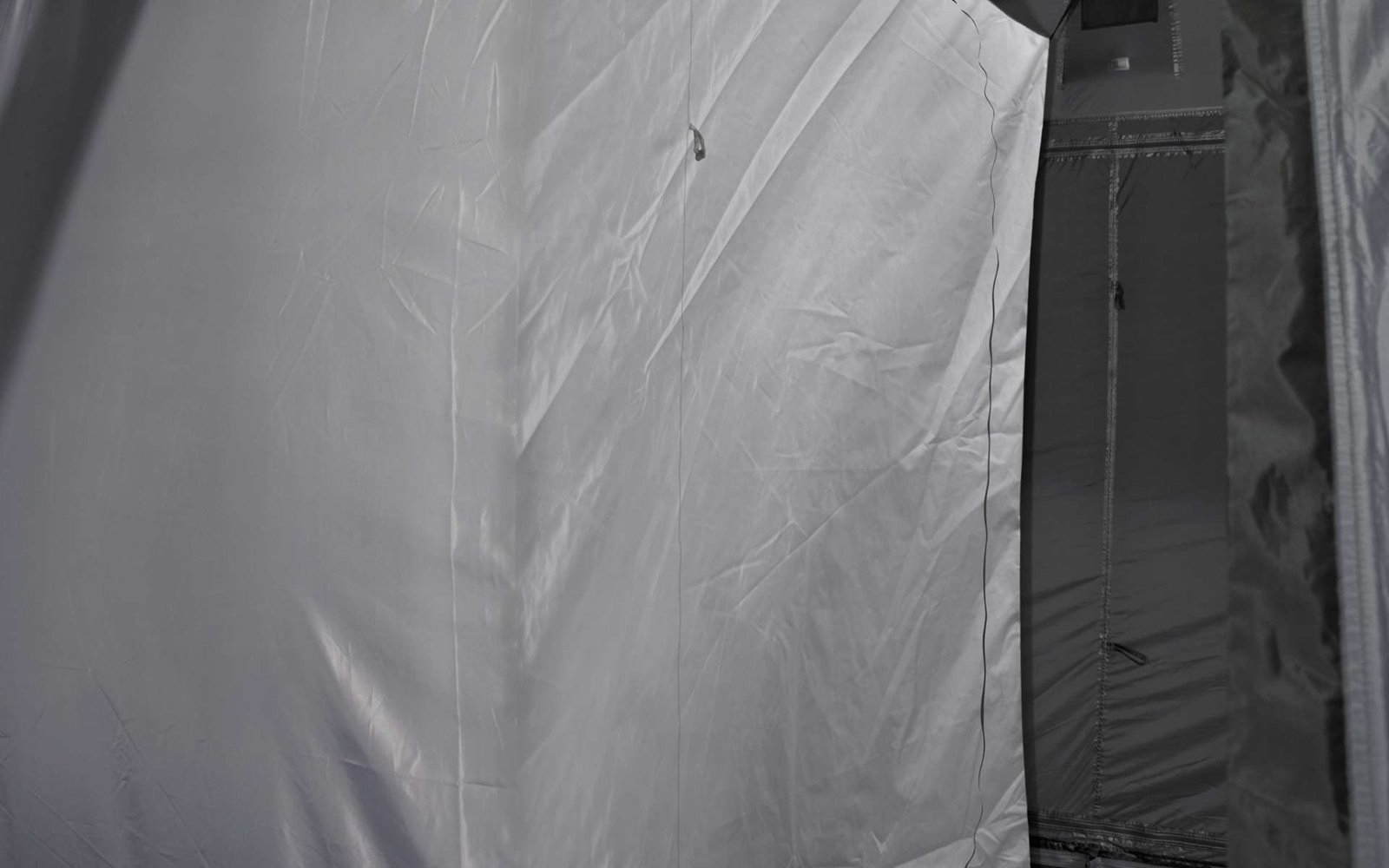 Nahaufnahme einer weißen Gardine vor einem dunklen Fenster