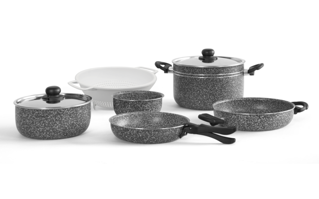 Plusieurs personnes assises à une table en bois avec des carnets, une tablette et un smartphone, une main tenant un stylo au premier plan