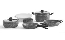 Plusieurs personnes assises à une table en bois avec des carnets, une tablette et un smartphone, une main tenant un stylo au premier plan