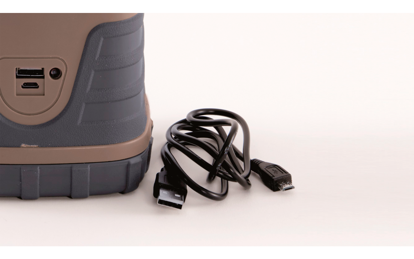 Brown and gray hiking shoe next to a black charging cable on a white background