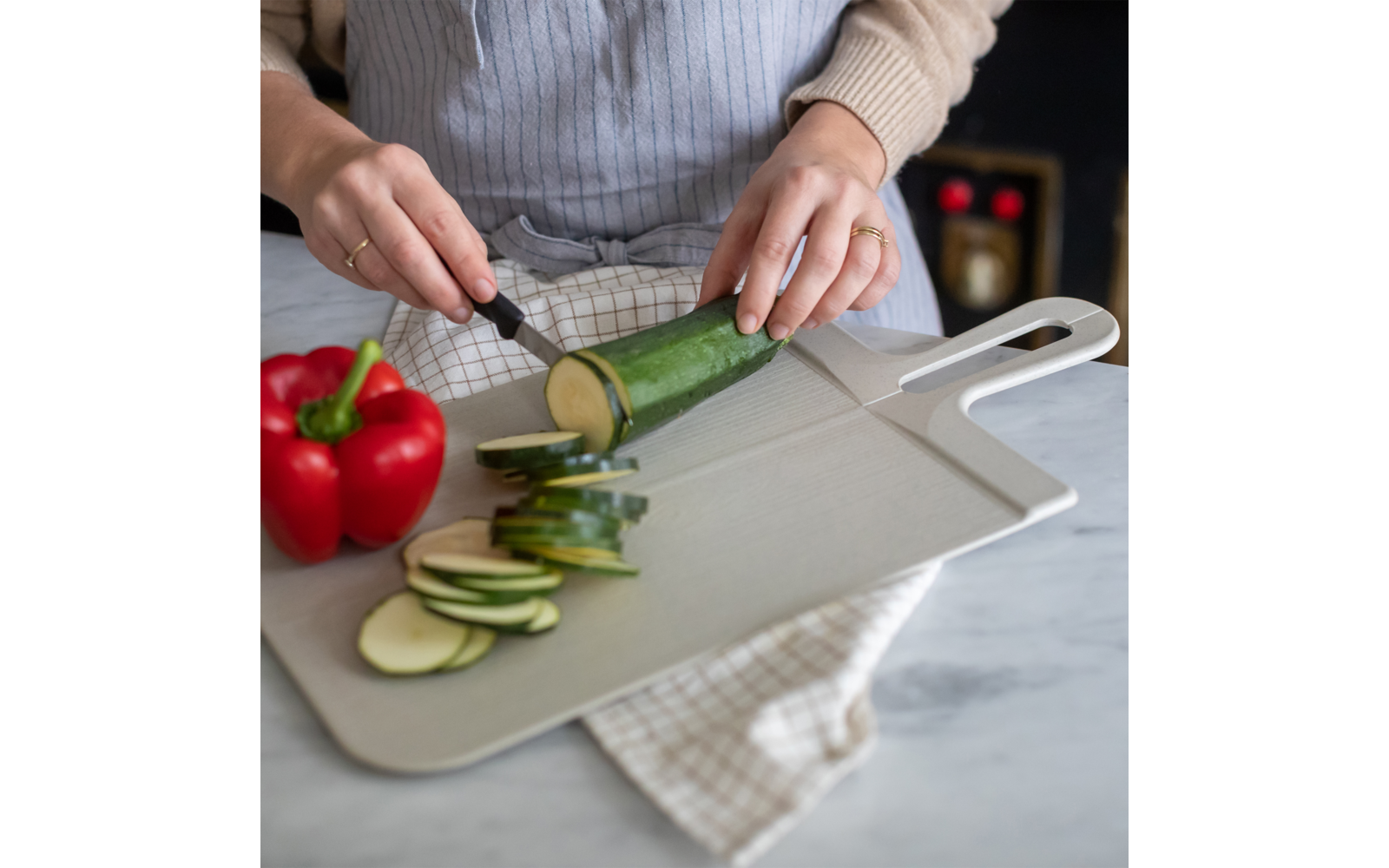 Een persoon snijdt een komkommer in plakjes op een snijplank