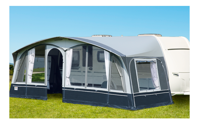 Una caravana con una gran tolda en un césped verde con clima soleado