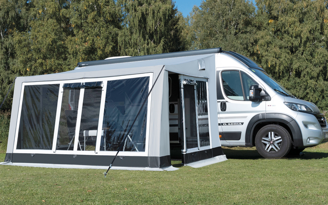 Wohnmobil steht auf einer Wiese vor einem blauen Himmel