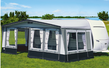 Großes graues Zelt mit Fenstern auf grüner Wiese unter blauem Himmel