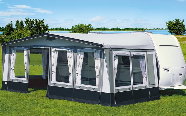 Gran tienda gris con ventanas sobre césped verde bajo cielo azul