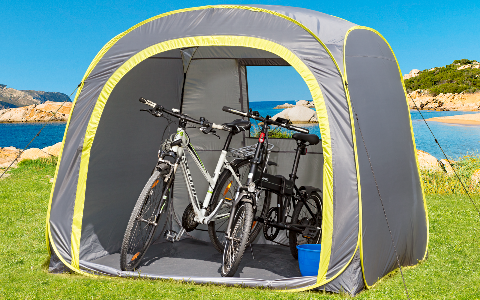 Zwei Fahrräder in einem grauen Zelt auf einer Wiese am Meer