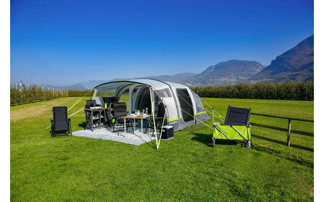 Zelt auf grünem Gras mit zwei Stühlen und Bergen im Hintergrund