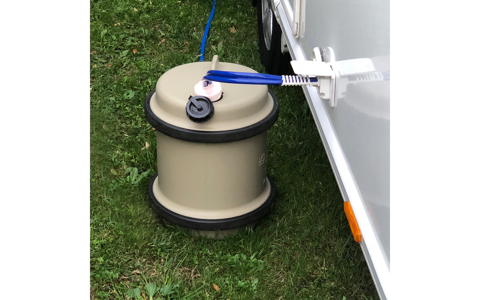 Erdanker mit Aufwickeleinrichtung auf Rasen neben einem weißen Fahrzeug