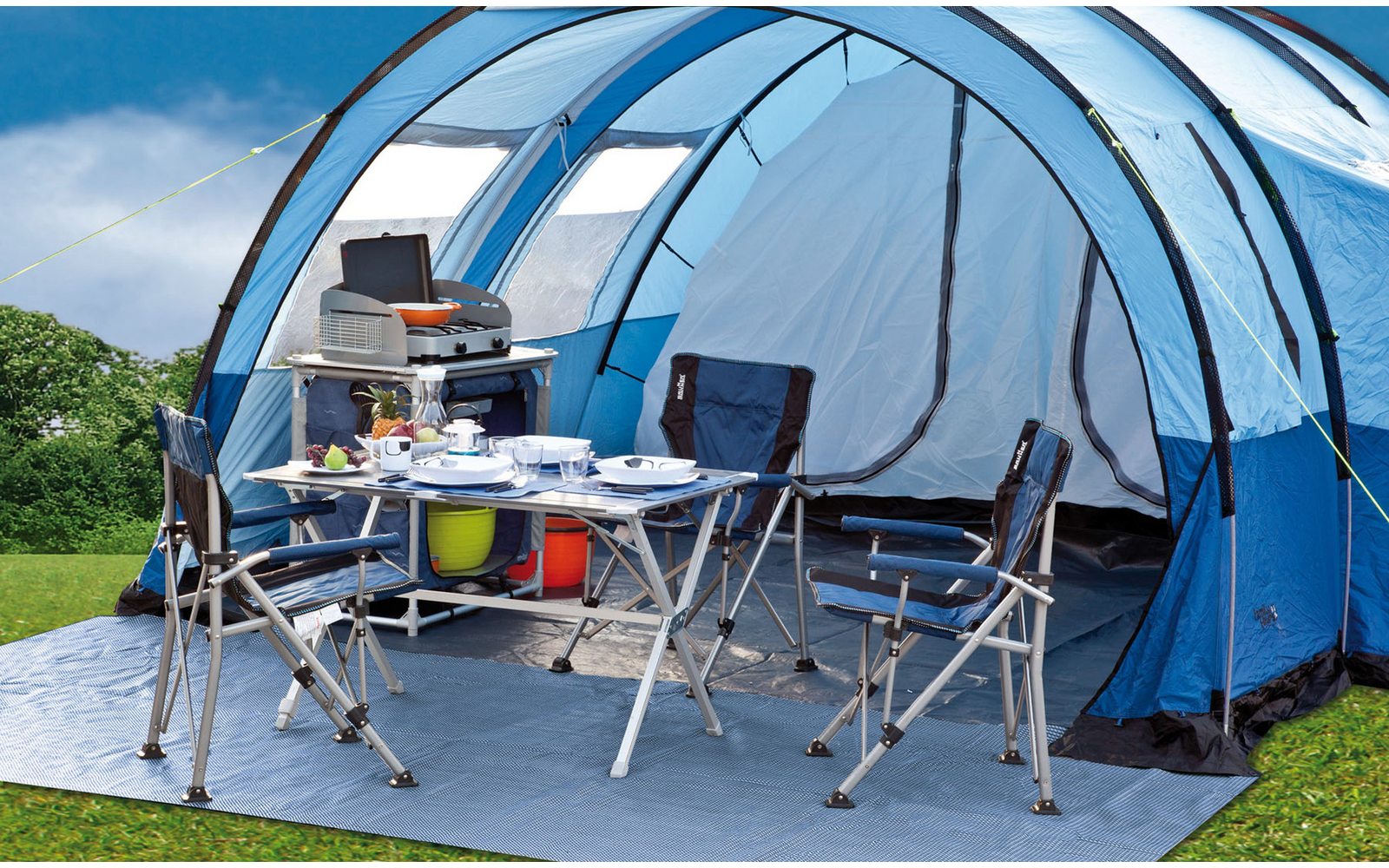 Gazebo da campeggio blu con sedie da campeggio e tavolo su prato